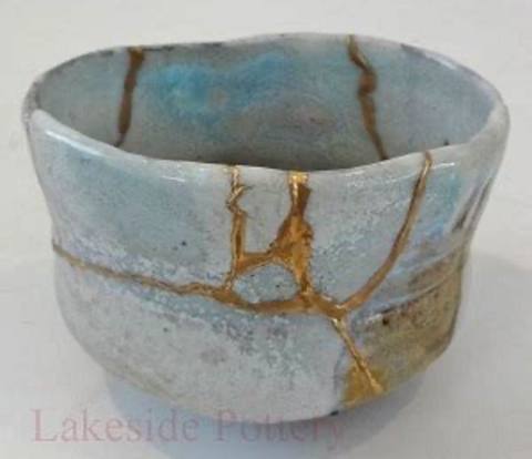 A ceramic bowl repaired in the kintsugi style, its cracks filled and traced in gold